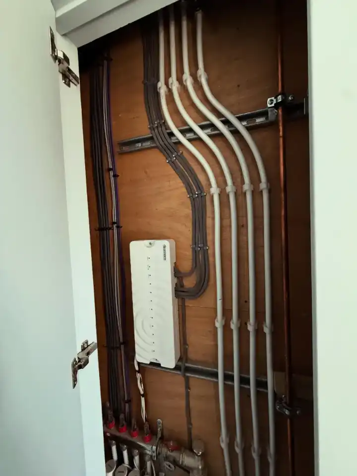 Inside a cupboard: neatly dressed cable runs clipped in parallel down the back board, fitted by FM Electrical